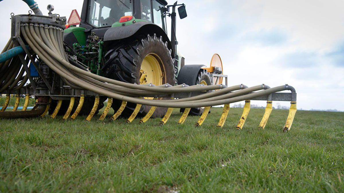 Tractor applying manure-based fertilizer through nutrient recovery equipment on farmland