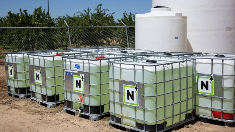 Large liquid fertilizer containers lined up at a farm-based production facility