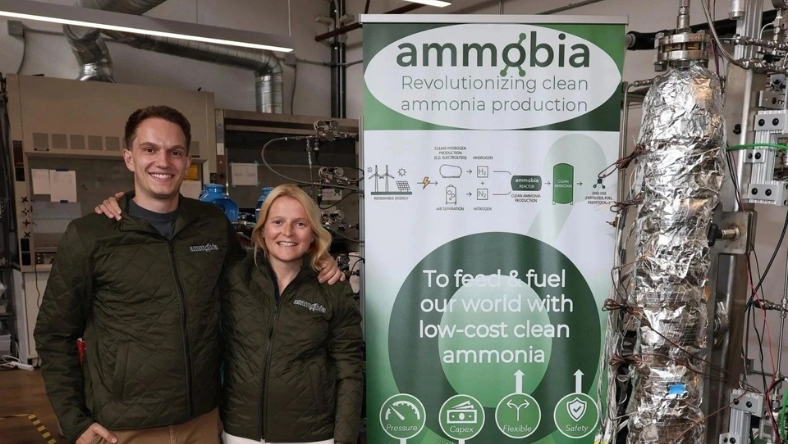 Ammobia team standing beside ammonia production equipment and banner